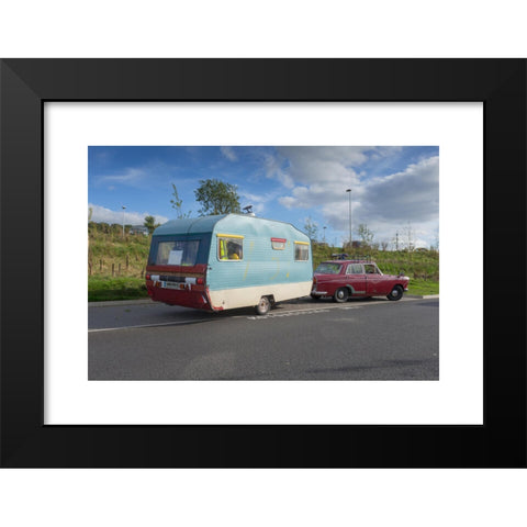 1960's Image Collection by Peter Lopeman - Black Modern Wood Framed Art Print Titled: Tradition caravan trailer from the 1960s being towed by an old car from the same period, parked at a motorway services