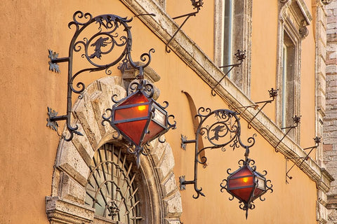 Italy- Umbria- Assisi. Wrought iron dragon lights on a wall above an entrance. Black Ornate Wood Framed Art Print with Double Matting by Eggers, Julie